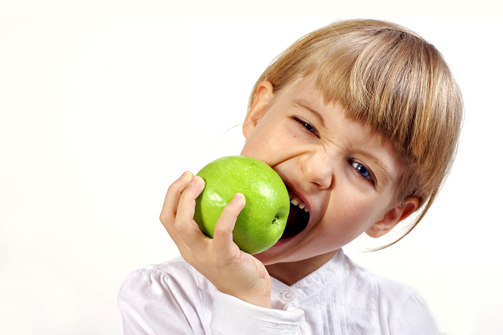 Mädchen beißt in einen grünen Apfel